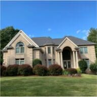 Large two-story brick and stone residential house with arched entrance