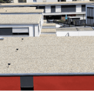 Modern commercial building rooftop with gravel surface and red accent strip